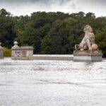 Lion statues are visible above a bridge that is submerged in water