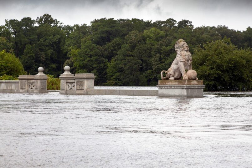 Lion statues are visible above a bridge that is submerged in water