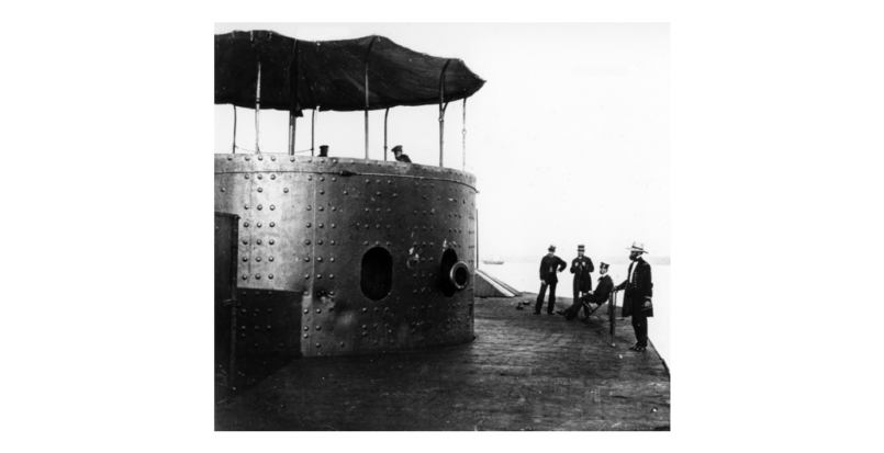 A picture of 4 men on deck outside of a turret looking into the turret at 2 men.